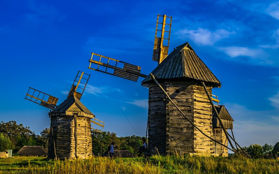 a couple of windmills sitting on top of a lush green field