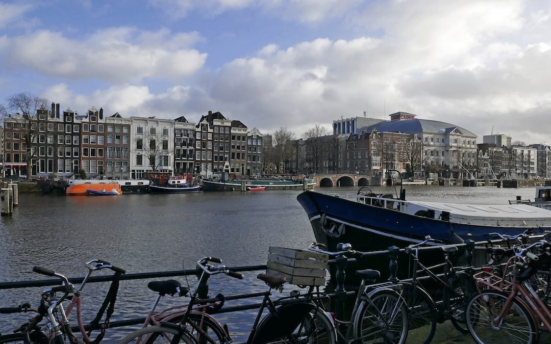 a row of bikes parked next to a body of water