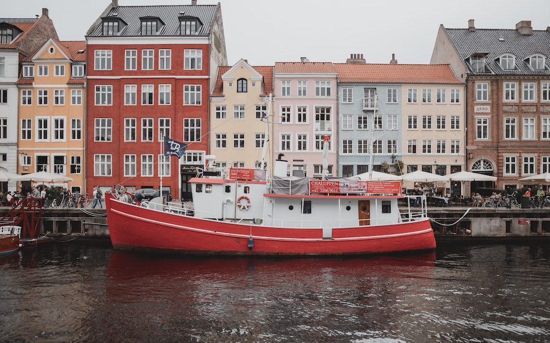 white and orange boat on water near buildings