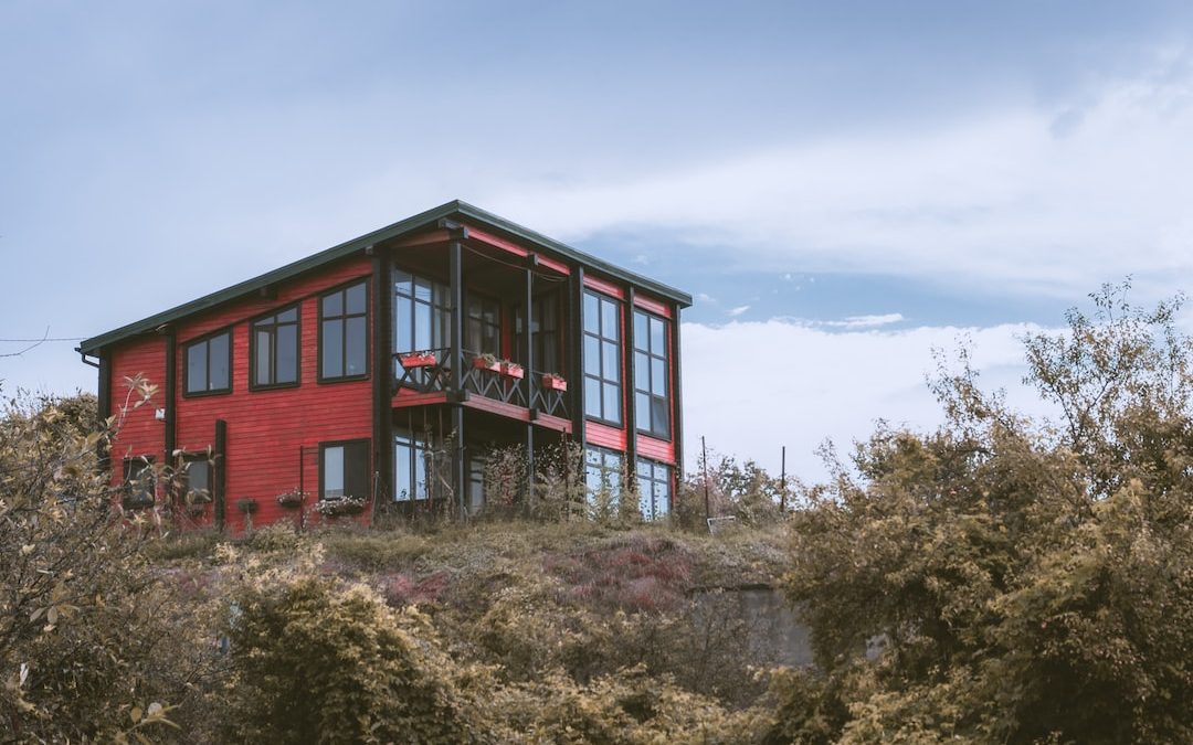 red and black wooden house surrounded by green trees under blue sky during daytime