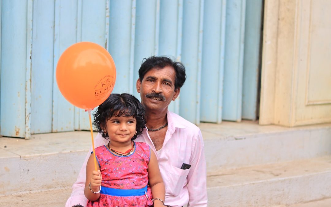 a man and a little girl holding a balloon