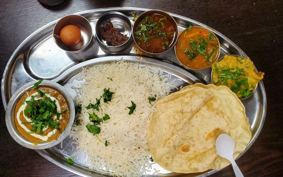 a silver plate topped with rice and different types of food