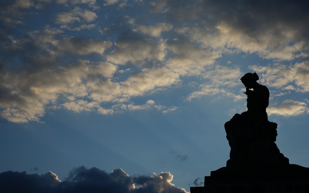 a silhouette of a person standing on top of a statue