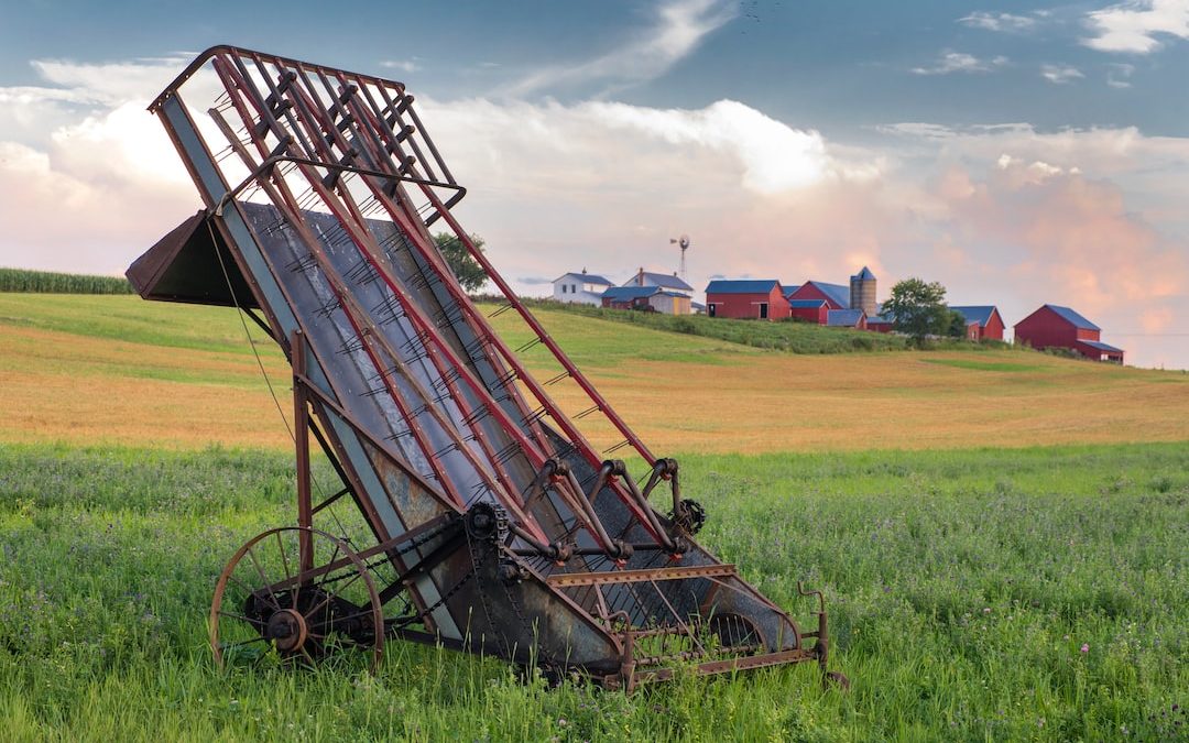 grey and red metal harvester machine on green field