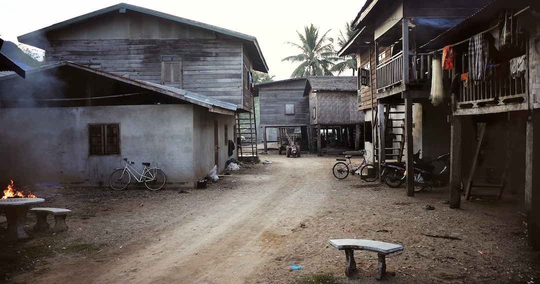 a dirt road in a village with buildings and bicycles