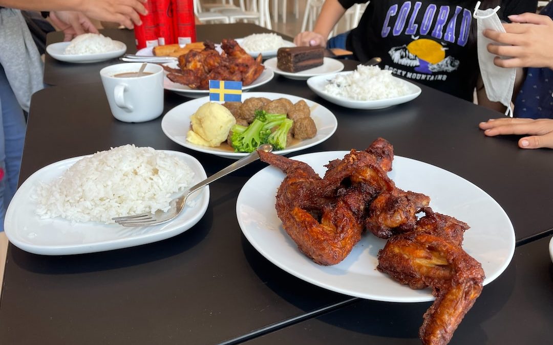 a group of people sitting at a table with plates of food