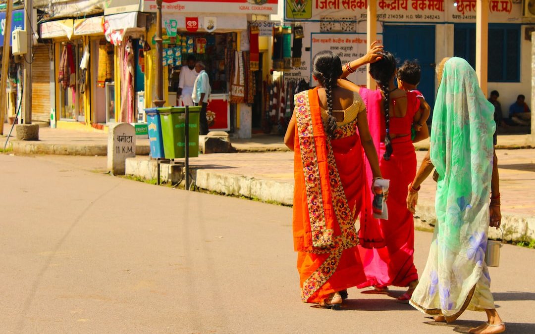 woman in red and white sari dress walking on sidewalk during daytime