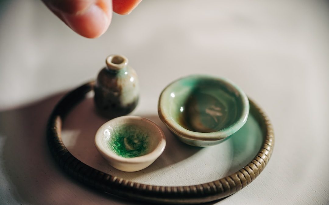 person holding 2 green and white ceramic bowls