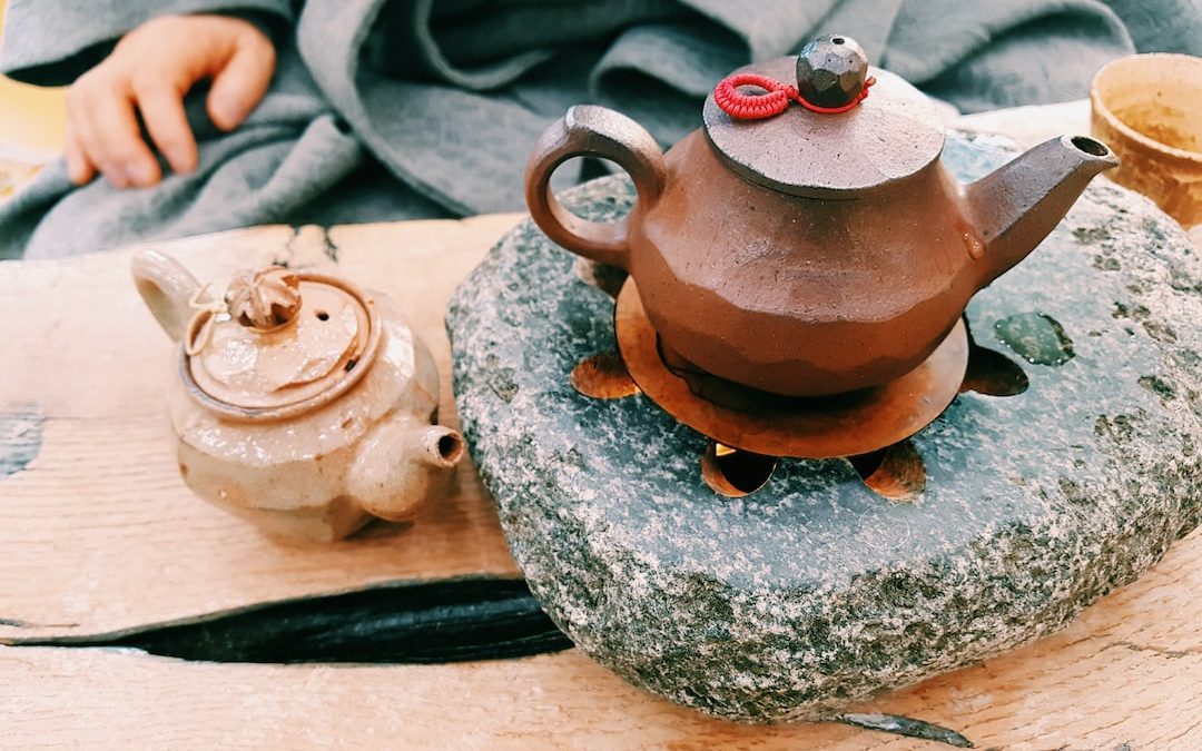 brown clay teapot on heated stone