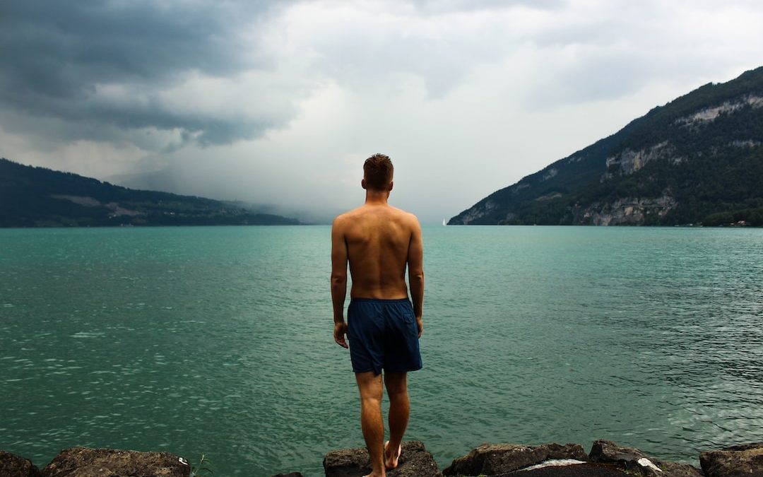 man wearing black shorts standing in front of body of water