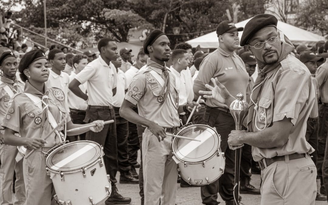 grayscale photo of men in white shirt and pants playing drum