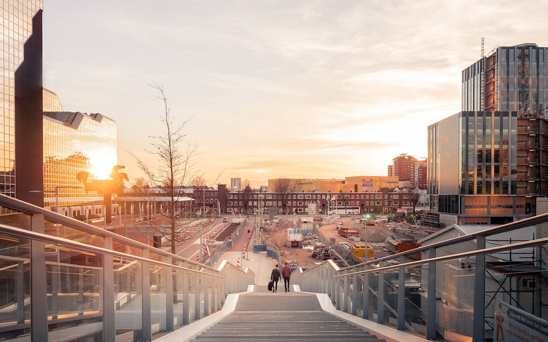 architectural structure photography of two people on stairs near buildings