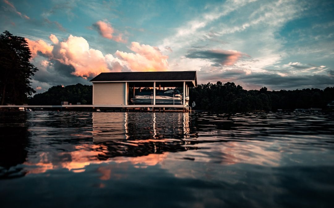 white wooden house on water under blue sky and white clouds during daytime