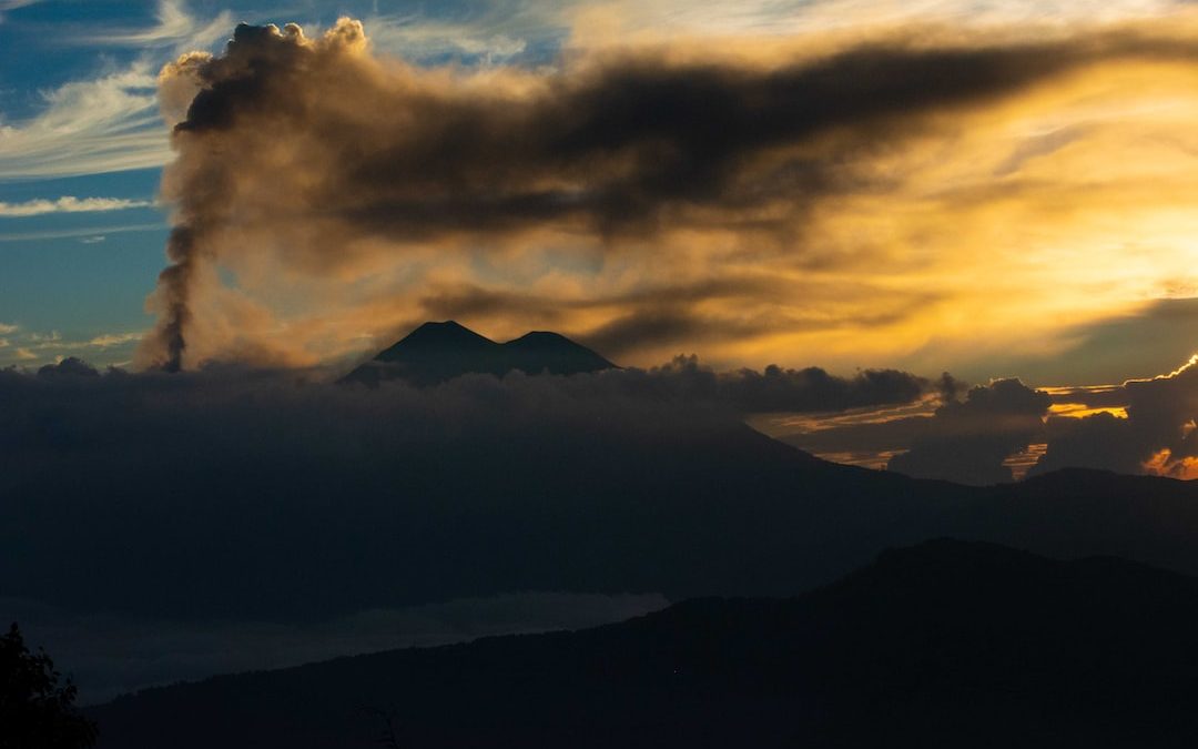 a mountain covered in clouds at sunset