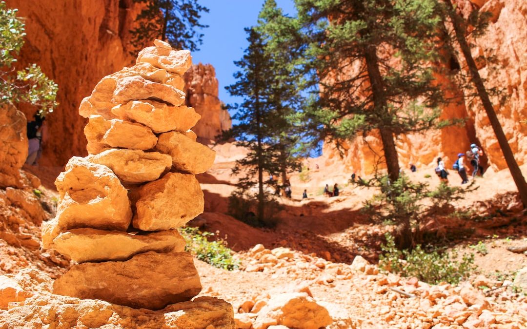 stone cairn on side of cliff overlooking trees at daytime