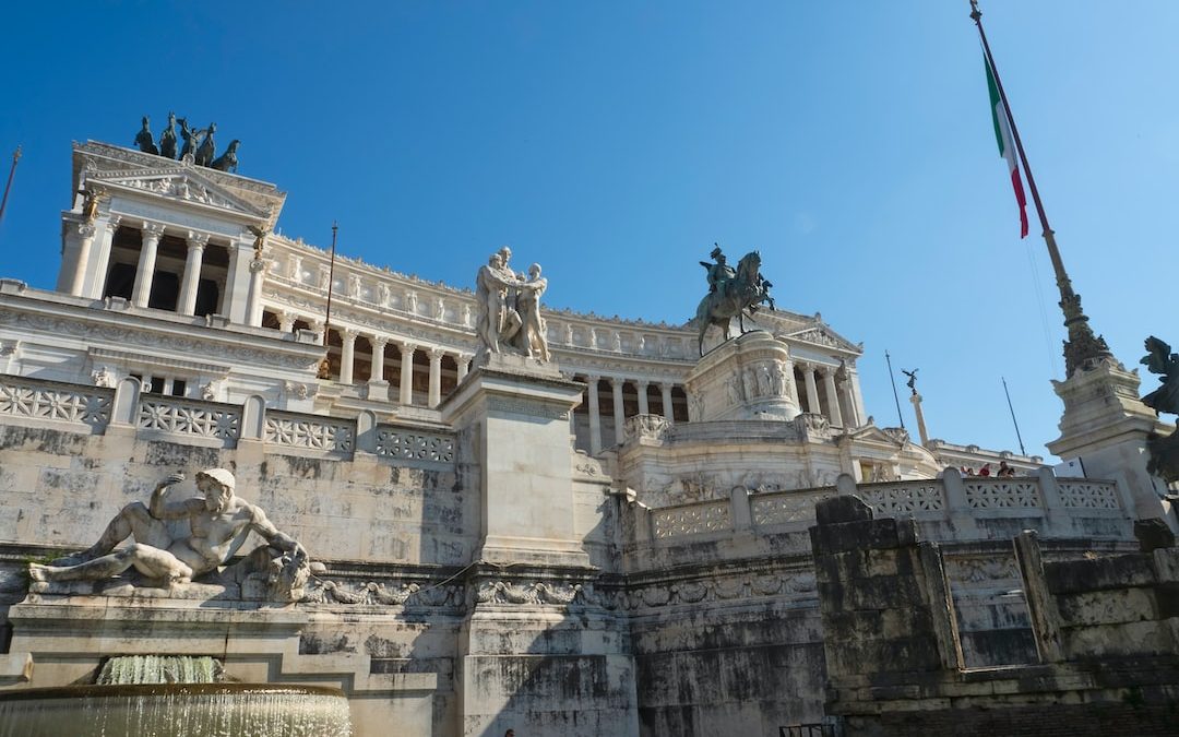 a stone building with statues and a flag on top