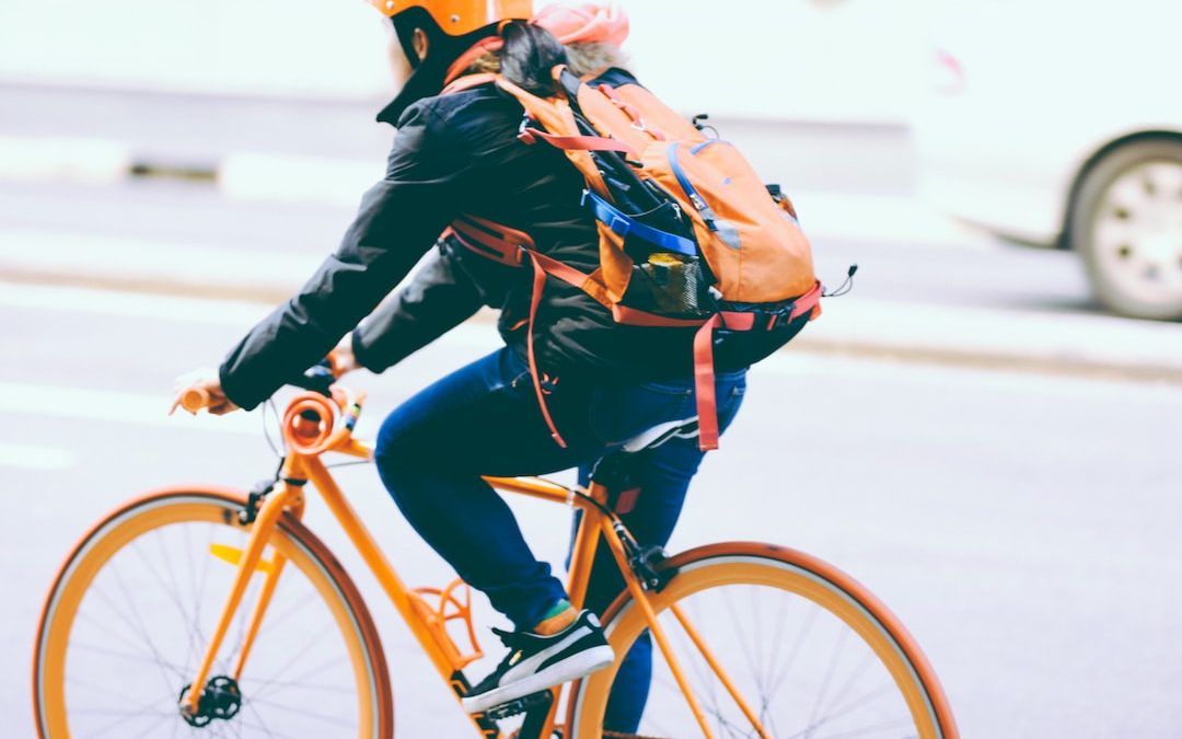 closeup photo of person riding a orange bicycle