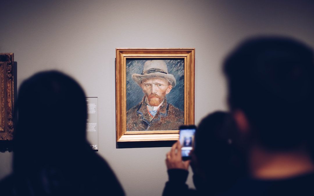 person taking picture of man wearing brown hat painting