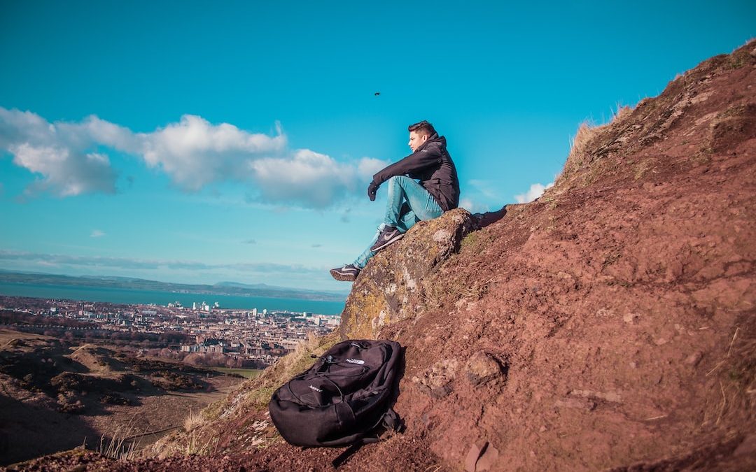 man sitting on mountain cliff