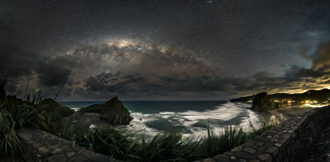 a rocky beach with a body of water and a cloudy sky