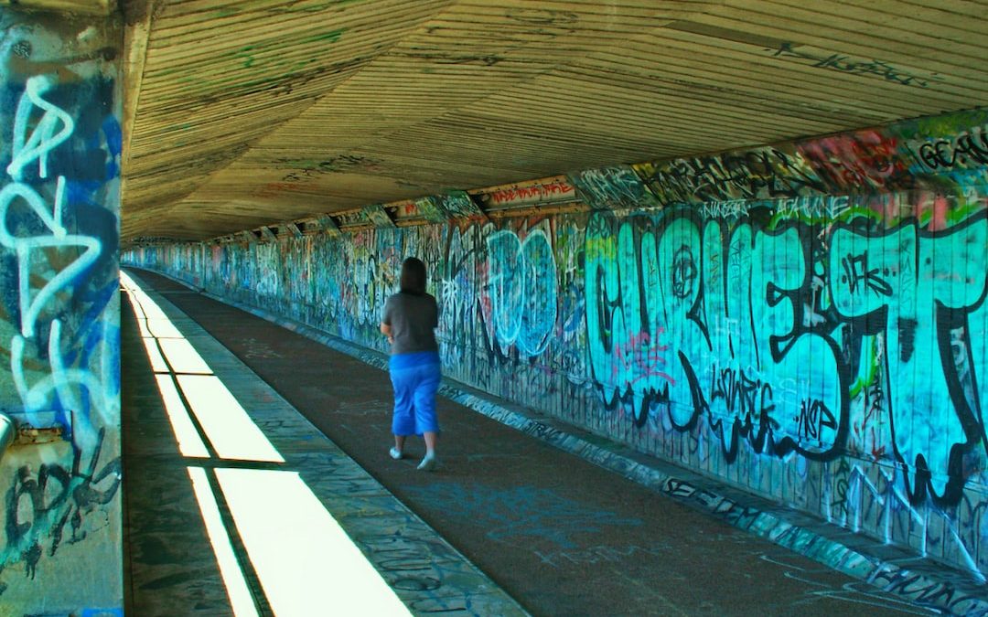 a person walking down a walkway covered in graffiti