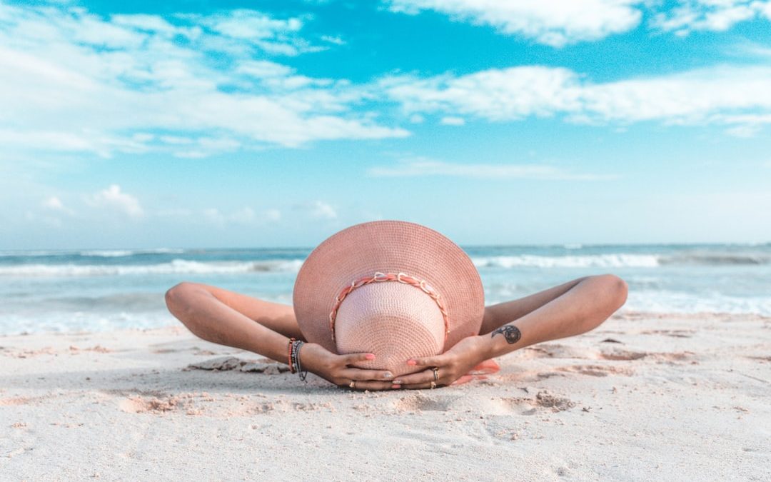 woman in brown sun hat lying on sand during daytime