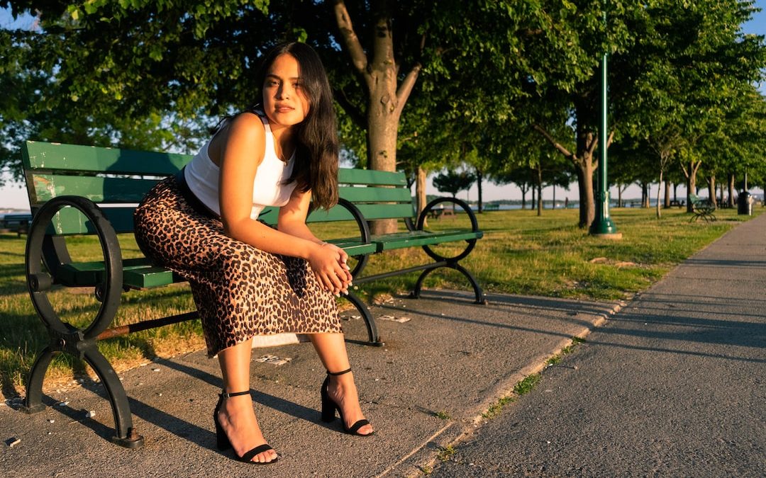 woman in white tank top and black and white polka dots skirt sitting on bench during