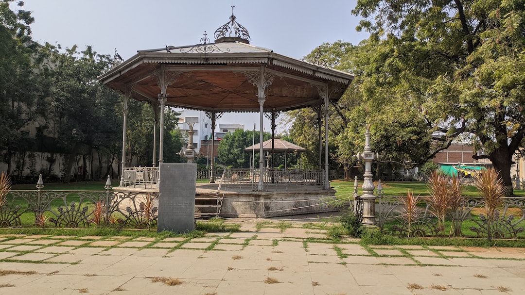 a gazebo in a park with a fountain in the middle