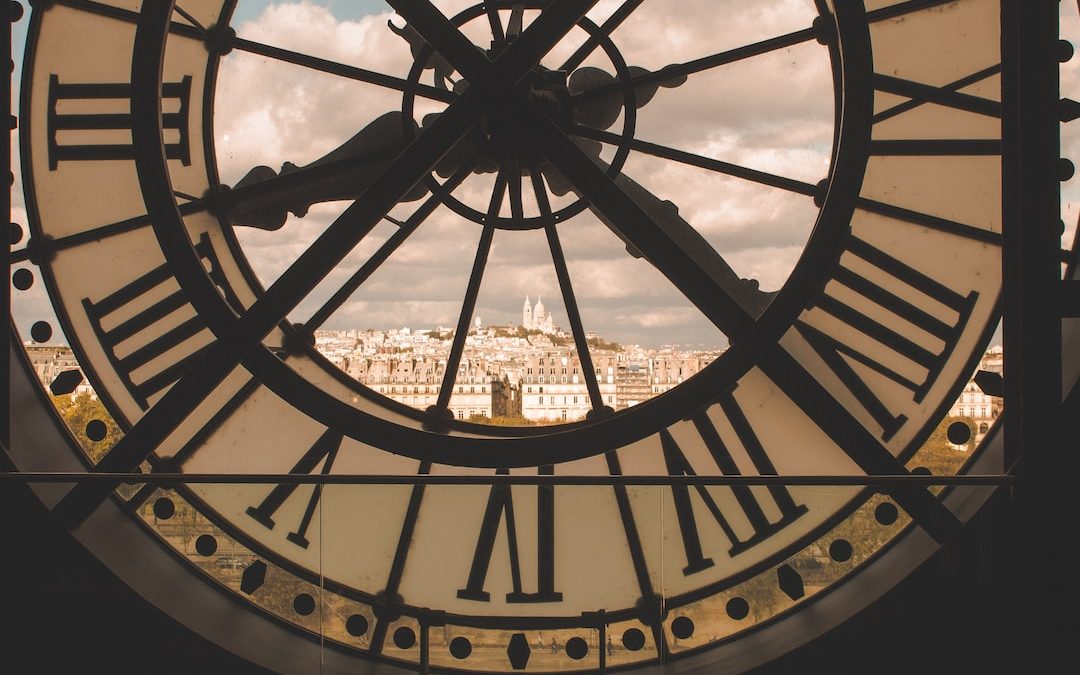 a large clock with roman numerals and a city in the background