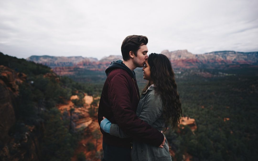 man kissing woman's forehead