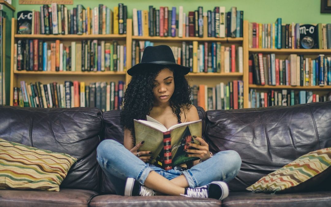 woman reading a book while sitting on black leather 3-seat couch