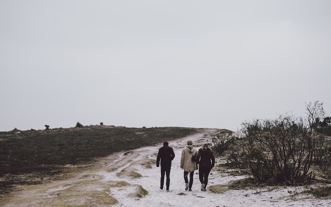 three person walking on snow covered field