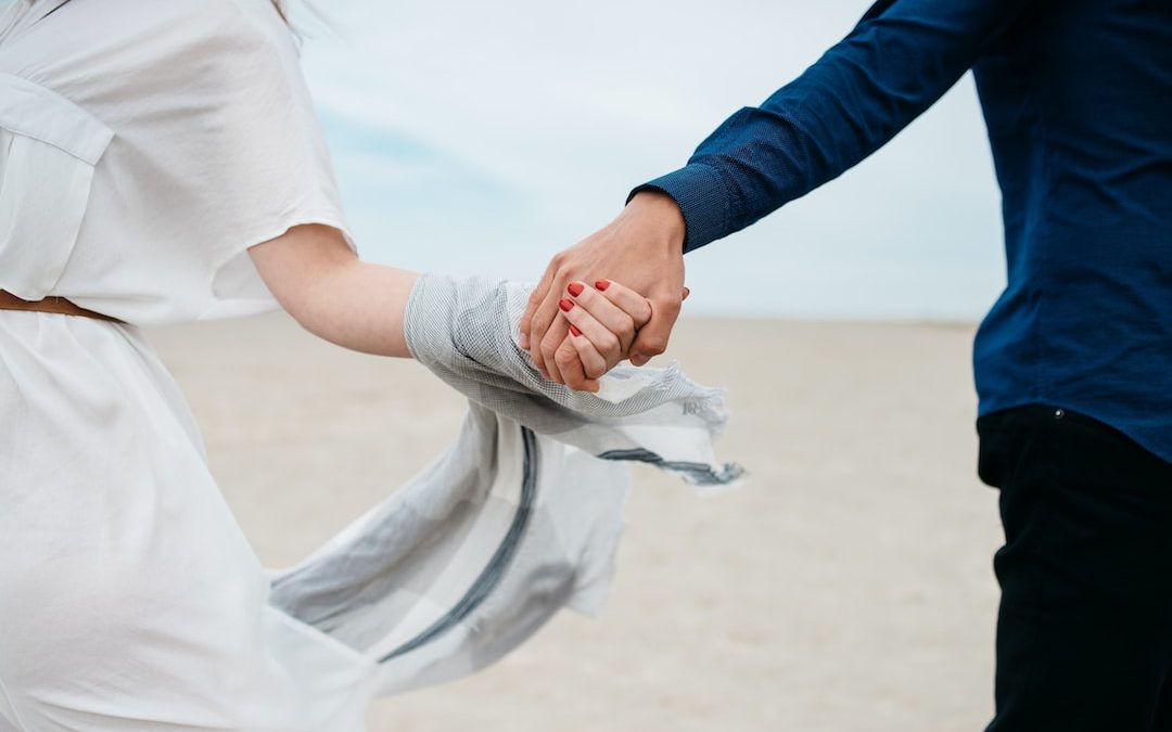 man and woman holding hands together in field during daytime