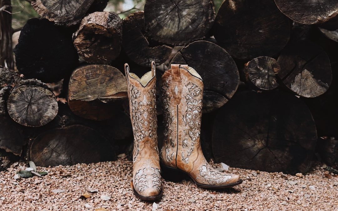 pair of brown leather cowboy boots near firewood