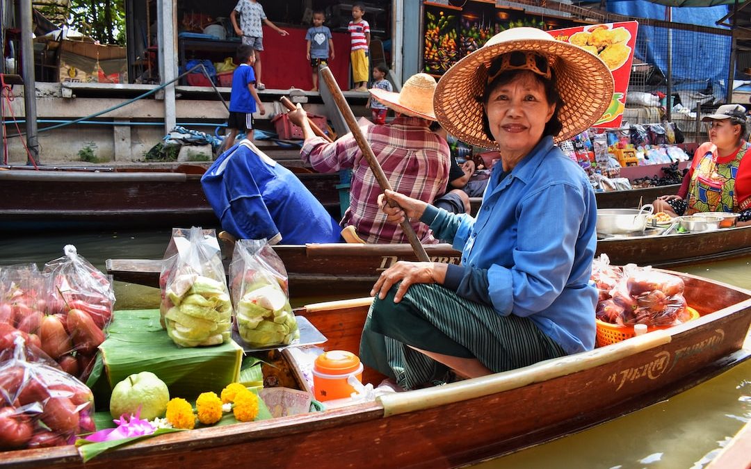 woman in blue dress shirt and brown straw hat sitting on brown wooden boat