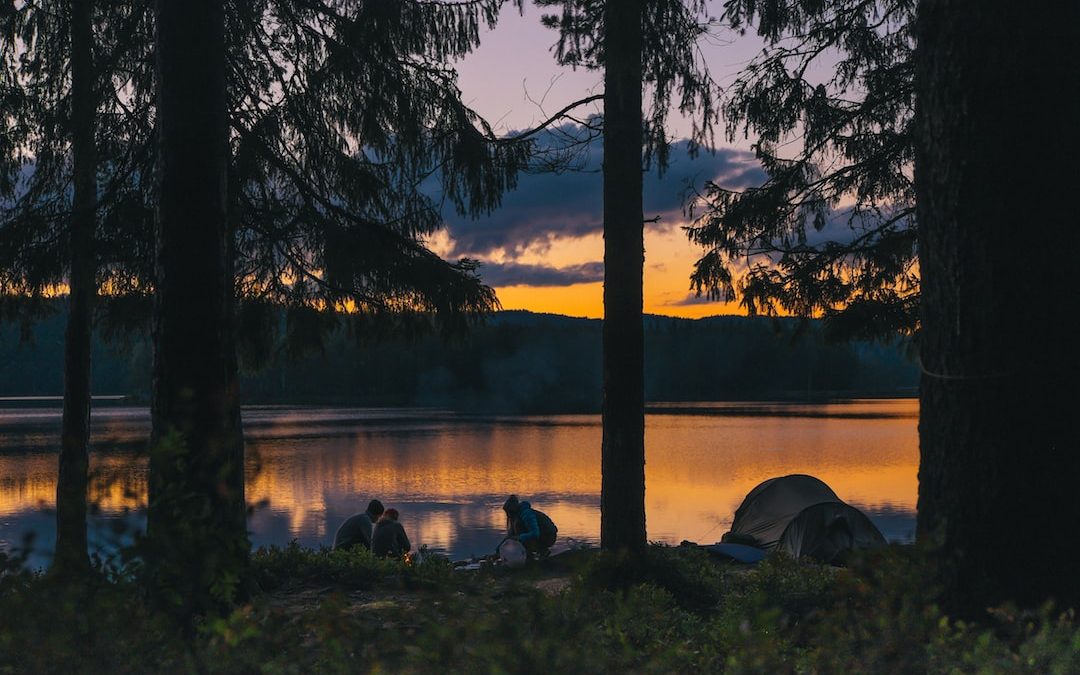 people beside body of water at golden hour