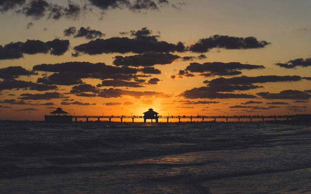 silhouette photo of dock with huts during golden hour