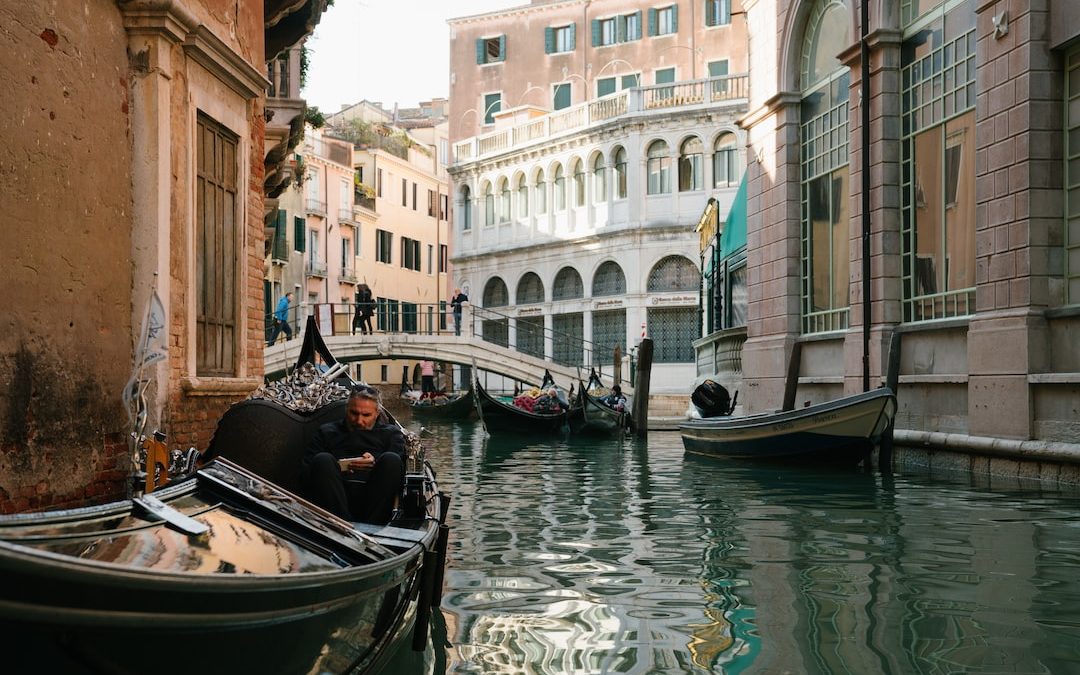 people riding on boat on river near buildings during daytime