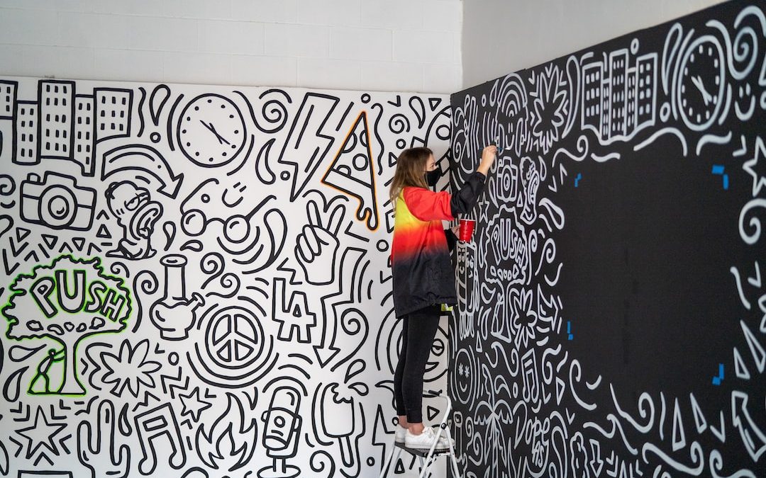 woman in black pants and orange jacket standing beside wall with graffiti