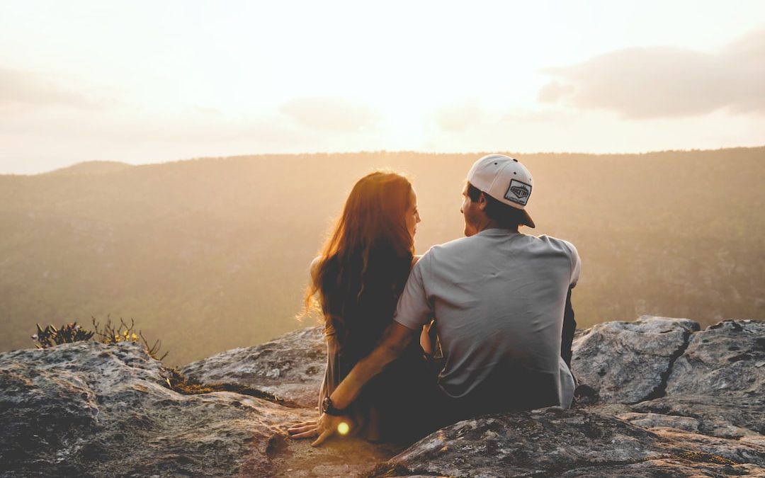 man and woman sitting on rock during daytime