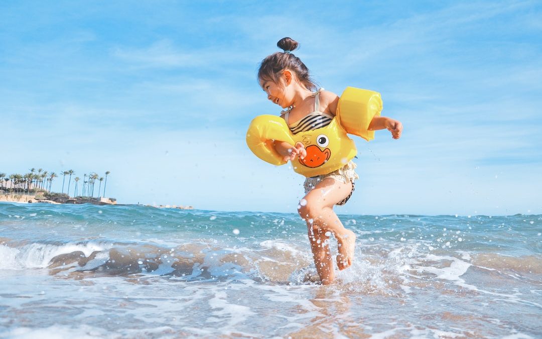 girl playing beside body of water during daytime