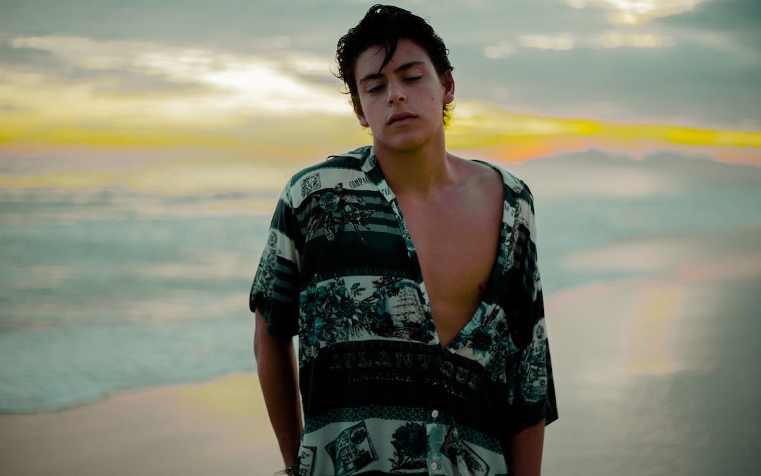 man wearing black and teal shirt on sea shore