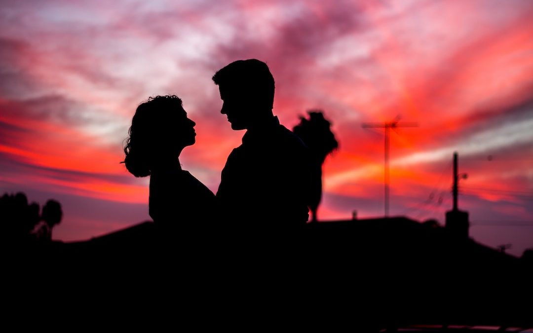 silhouette of man and woman facing each other during golden hour