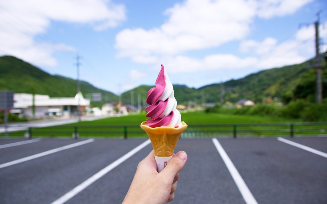 person holding strawberry and vanilla ice cream on cone