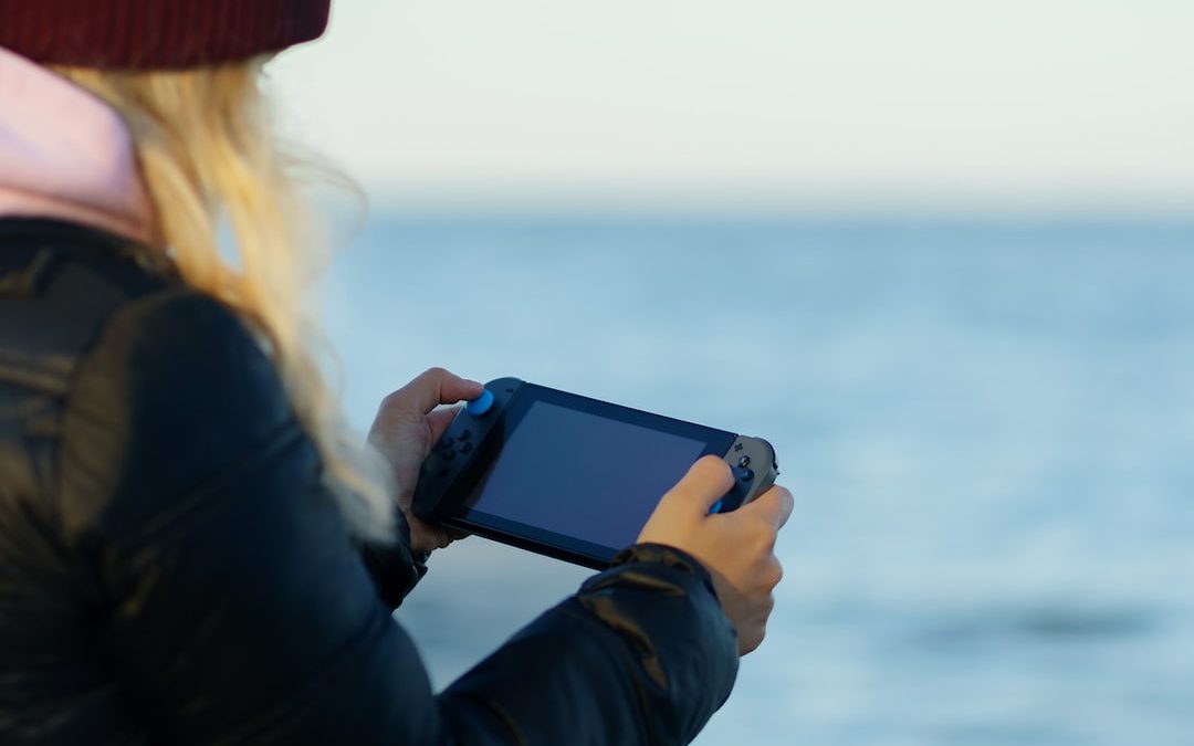 a woman holding a game controller in front of a body of water