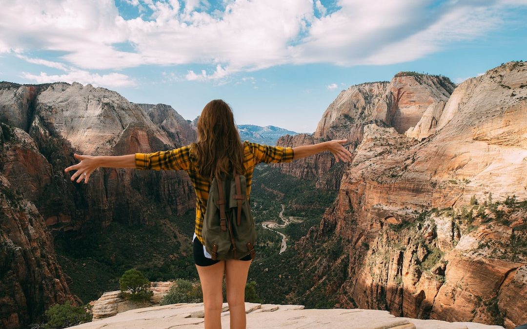 woman spreading her hands white standing on mountain cliff