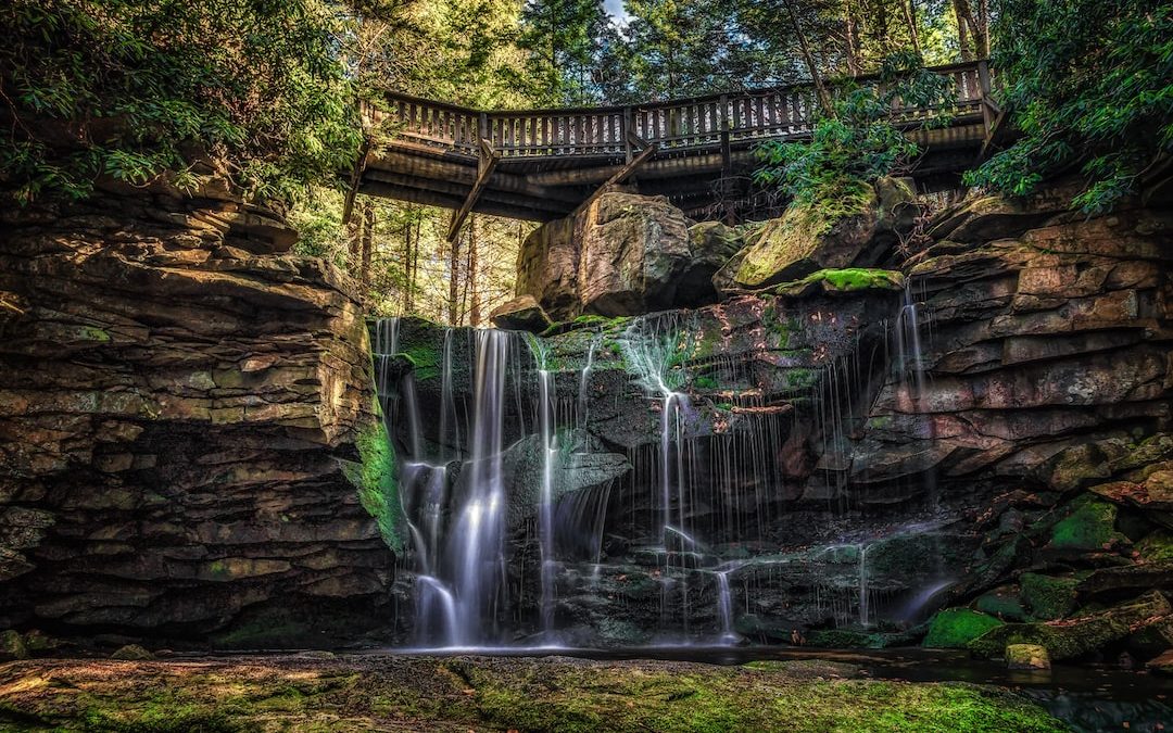 waterfalls near wooden bridge and trees wallpaper
