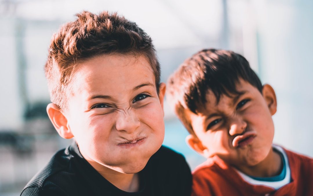 shallow focus photography of two boys doing wacky faces