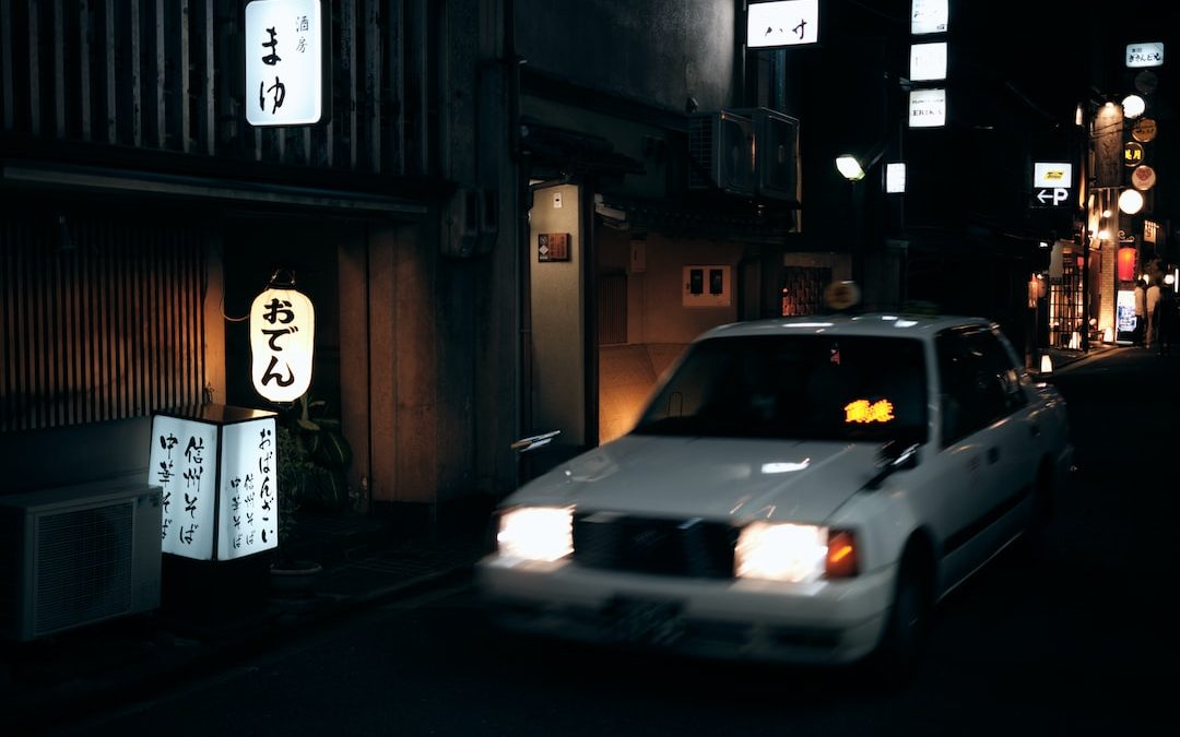 a white car driving down a street at night