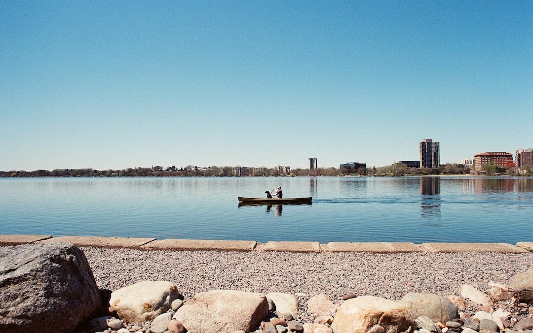 person in black shirt standing on brown rock near body of water during daytime